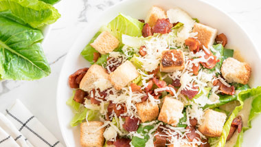 salad with cheese bacon and croutons on a marble countertop